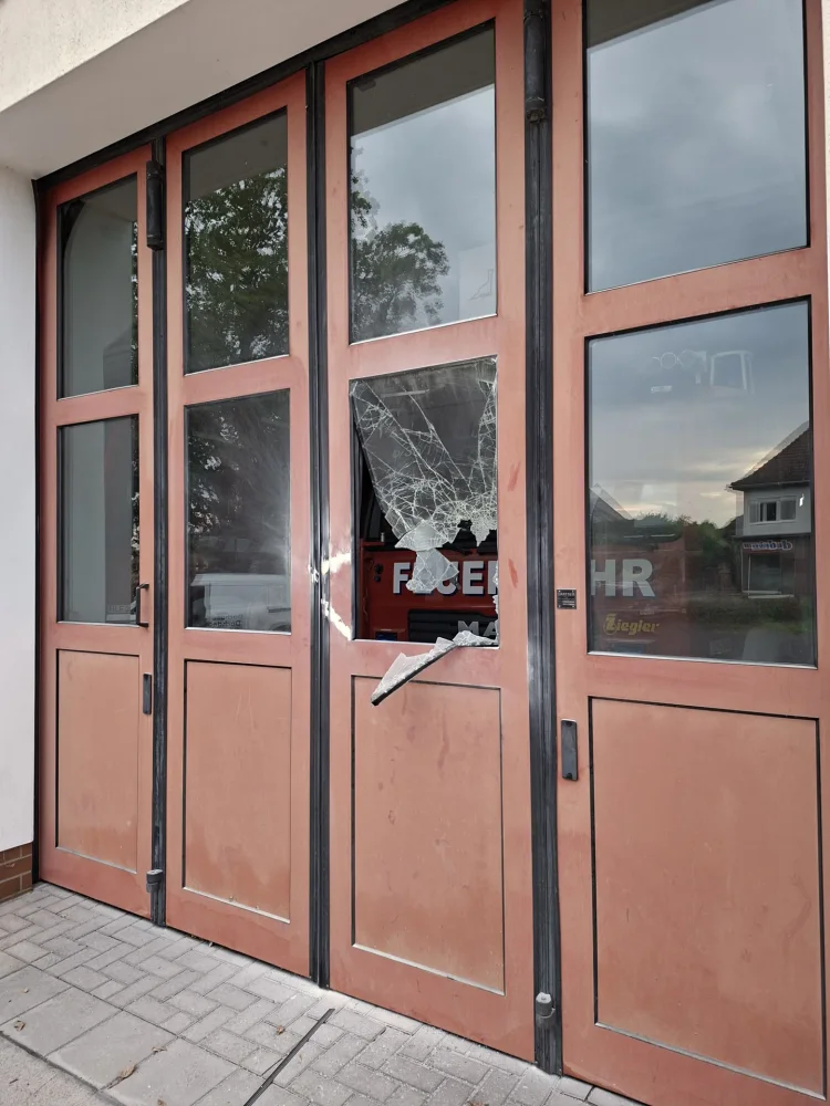 Zerstörte Garagentorscheibe am Feuerwehrgerätehaus Calau, dahinter ein Feuerwehrfahrzeug